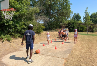 Børn deltager i en udendørs basketball-aktivitet med en instruktør i Domaine des Chênes Blancs, Provence.