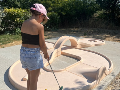 Kind speelt minigolf in openlucht op Domaine des Chênes Blancs vakantiedomein in Provence, Frankrijk.
