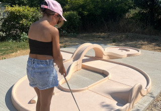 Barn spiller minigolf udendørs på Domaine des Chênes Blancs feriepark i Provence-Alpes-Côte d’Azur, Frankrig.