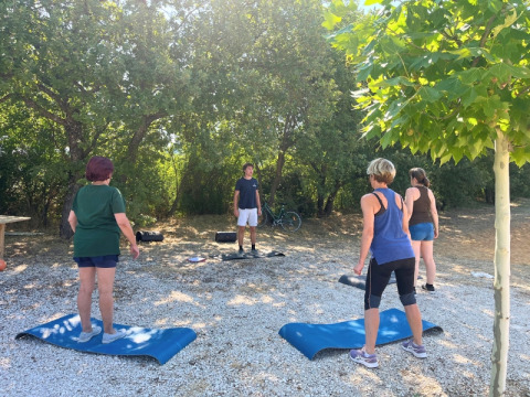 Udendørs træningssession i Domaine des Chênes Blancs feriepark med instruktør og deltagere på måtter.