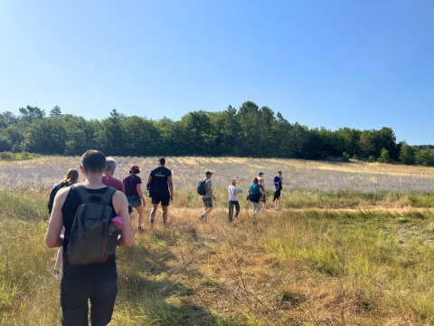 Un groupe de personnes randonne près de Saint-Saturnin-lès-Apt par une journée ensoleillée et ciel bleu.