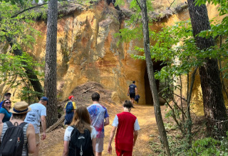 Un grupo de personas camina hacia una cueva rocosa cerca de Saint-Saturnin-lès-Apt en Provenza, Francia.