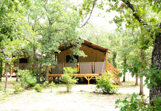 PREMIUM Lodge Safarizelt im Domaine des Chênes Blancs, Frankreich, umgeben von grünen Bäumen.
