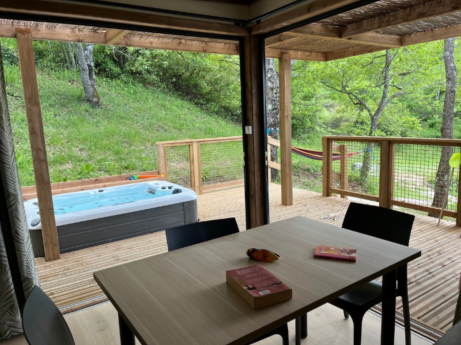 Uitzicht vanuit Cottage «Séouvo» op Camping Le Luberon in Frankrijk met terras, jacuzzi en hangmat.