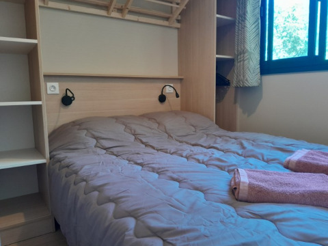 Camera da letto nella casa sull'albero Cottage «Séouvo» con letto matrimoniale e asciugamani a Le Luberon.