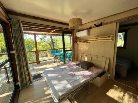 Vista interna della casa sull’albero Cottage «Séouvo» al Campeggio Le Luberon, letto e terrazzo.