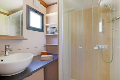 Bagno moderno con lavabo, ampia doccia, finestra e scaffali in una casa sull’albero al Le Luberon, Francia.