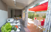 Bright kitchen and covered terrace with dining area at Cottage Romarin, Campsite Le Luberon, France.