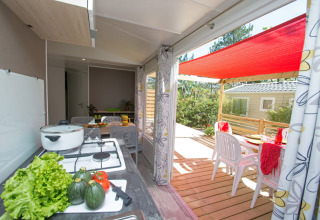 Cucina luminosa e terrazza coperta con tavolo nel Cottage Romarin al campeggio Le Luberon, Francia.