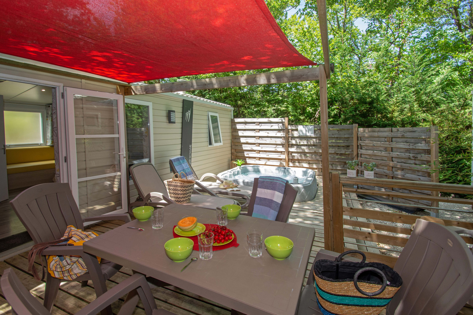 Buitenterras bij Cottage Romarin op Camping Le Luberon in Frankrijk, met eettafel en privé bubbelbad.