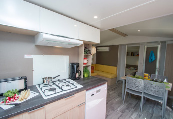 Cucina moderna e soggiorno nel Cottage Romarin al campeggio Le Luberon, Francia, con zona pranzo.