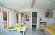 Interior of Cottage Romarin at Campsite Le Luberon in France, featuring a dining table and bright decor.
