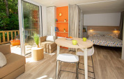 Bright, cozy interior of Cottage Evasion at Campsite Le Luberon, France, with lounge, dining, and bedroom.