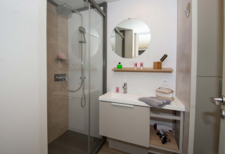 Bagno moderno nel Cottage Evasion presso il Campeggio Le Luberon, Francia, con doccia e lavandino.