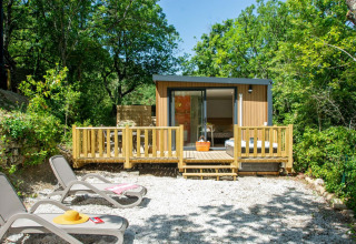 Vista esterna del Cottage Evasion con terrazza e lettini al campeggio Le Luberon in Francia.