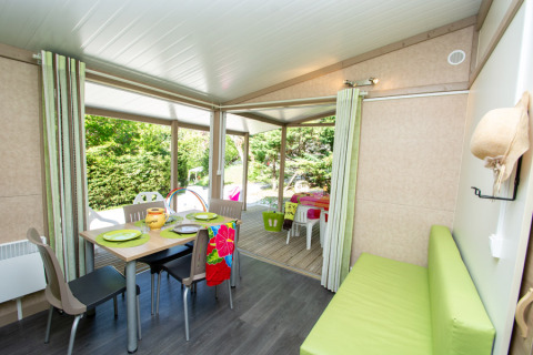 Interno di Cottage Lavande al campeggio Le Luberon, Francia, con tavolo da pranzo e terrazza.
