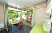 Interno di Cottage Lavande al campeggio Le Luberon, Francia, con tavolo da pranzo e terrazza.
