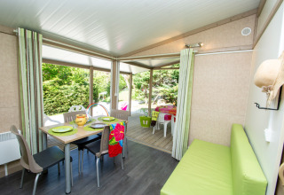 Interno di Cottage Lavande al campeggio Le Luberon, Francia, con tavolo da pranzo e terrazza.