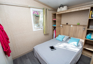 Camera da letto nel Cottage Lavande al Campeggio Le Luberon con letto matrimoniale, mensole e tablet.
