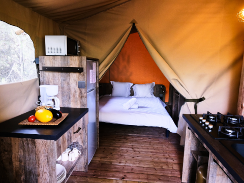 Premium-Safari-Zelt mit Küche und Doppelbett im Domaine des Chênes Blancs in Frankreich, Innenansicht.