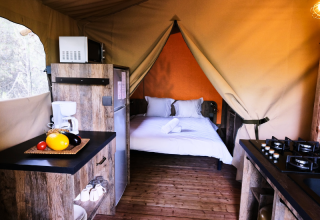 Premium-Safari-Zelt mit Küche und Doppelbett im Domaine des Chênes Blancs in Frankreich, Innenansicht.