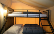 Bunk bed with crisp linens in a premium safari tent at Domaine des Chênes Blancs, located in France.