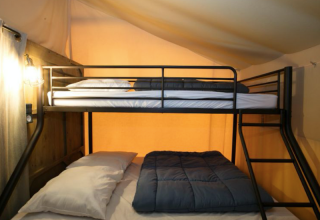 Etagenbett mit weißen und blauen Bettdecken in einem Premium-Safari-Zelt im Domaine des Chênes Blancs, Frankreich.