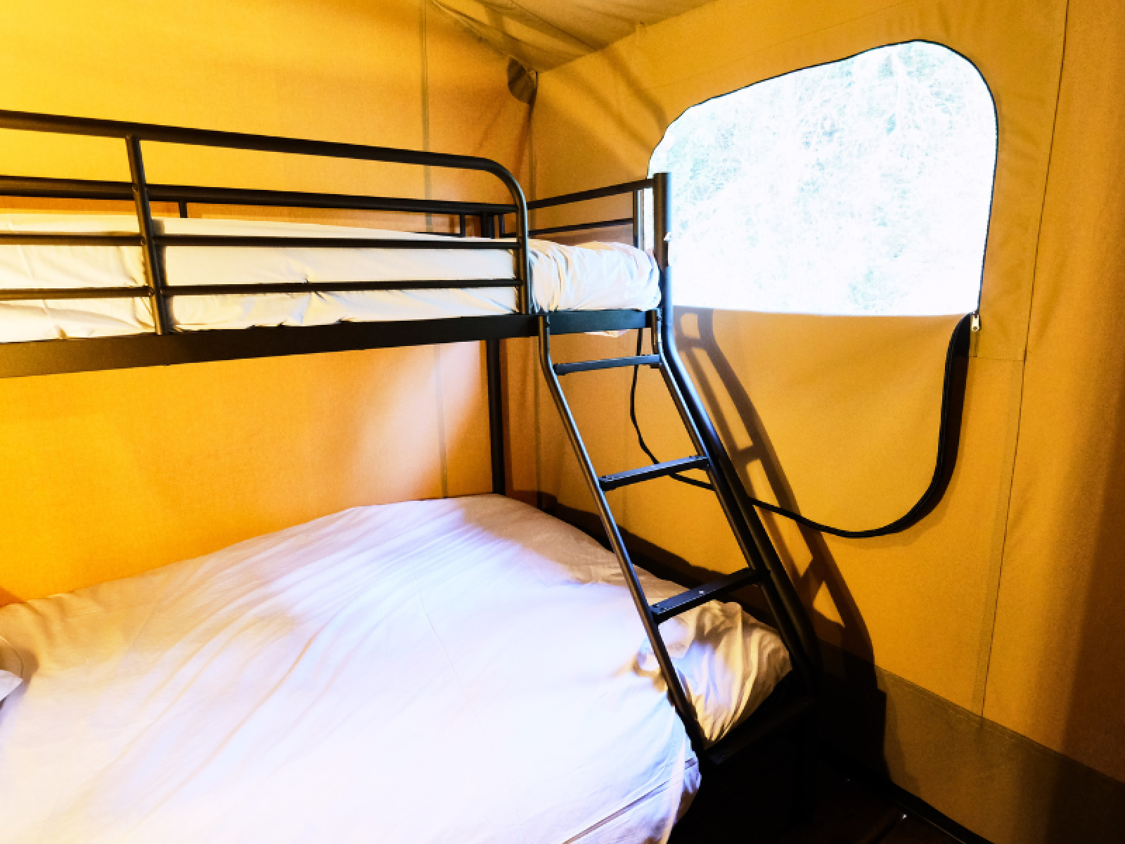 Interieur van PREMIUM Lodge safaritent met stapelbed en raam bij Domaine des Chênes Blancs in Frankrijk.