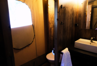 Badezimmer im PREMIUM Lodge Safarizelt im Domaine des Chênes Blancs, Frankreich, mit Waschbecken und Spiegel.