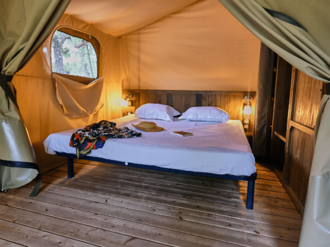 Interieur van een Lodge «COSY» safaritent bij Domaine des Chênes Blancs, Frankrijk, met houten vloer en bed.