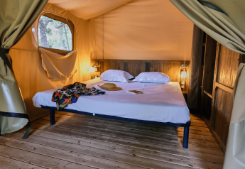 Indretning i en Lodge «COSY» safaritelte på Domaine des Chênes Blancs med trægulv og dobbeltseng.