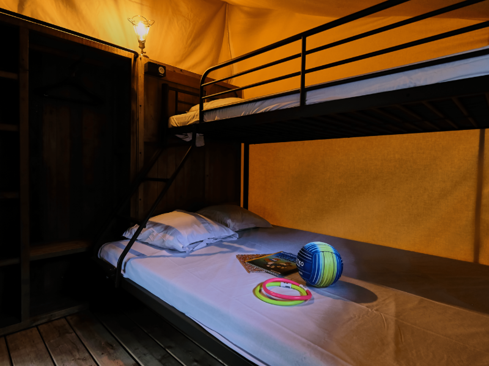 Interieur van Lodge COSY safaritent met stapelbed en speelgoed op het bed bij Domaine des Chênes Blancs, Frankrijk.