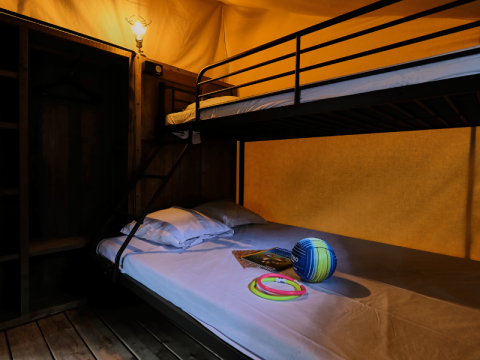 Interieur van Lodge COSY safaritent met stapelbed en speelgoed op het bed bij Domaine des Chênes Blancs, Frankrijk.