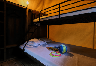 Interieur van Lodge COSY safaritent met stapelbed en speelgoed op het bed bij Domaine des Chênes Blancs, Frankrijk.
