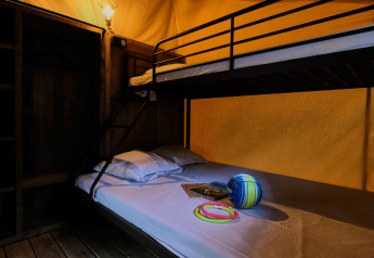 Indretning af Lodge COSY safari-telt med køjeseng og legetøj på sengen på Domaine des Chênes Blancs.