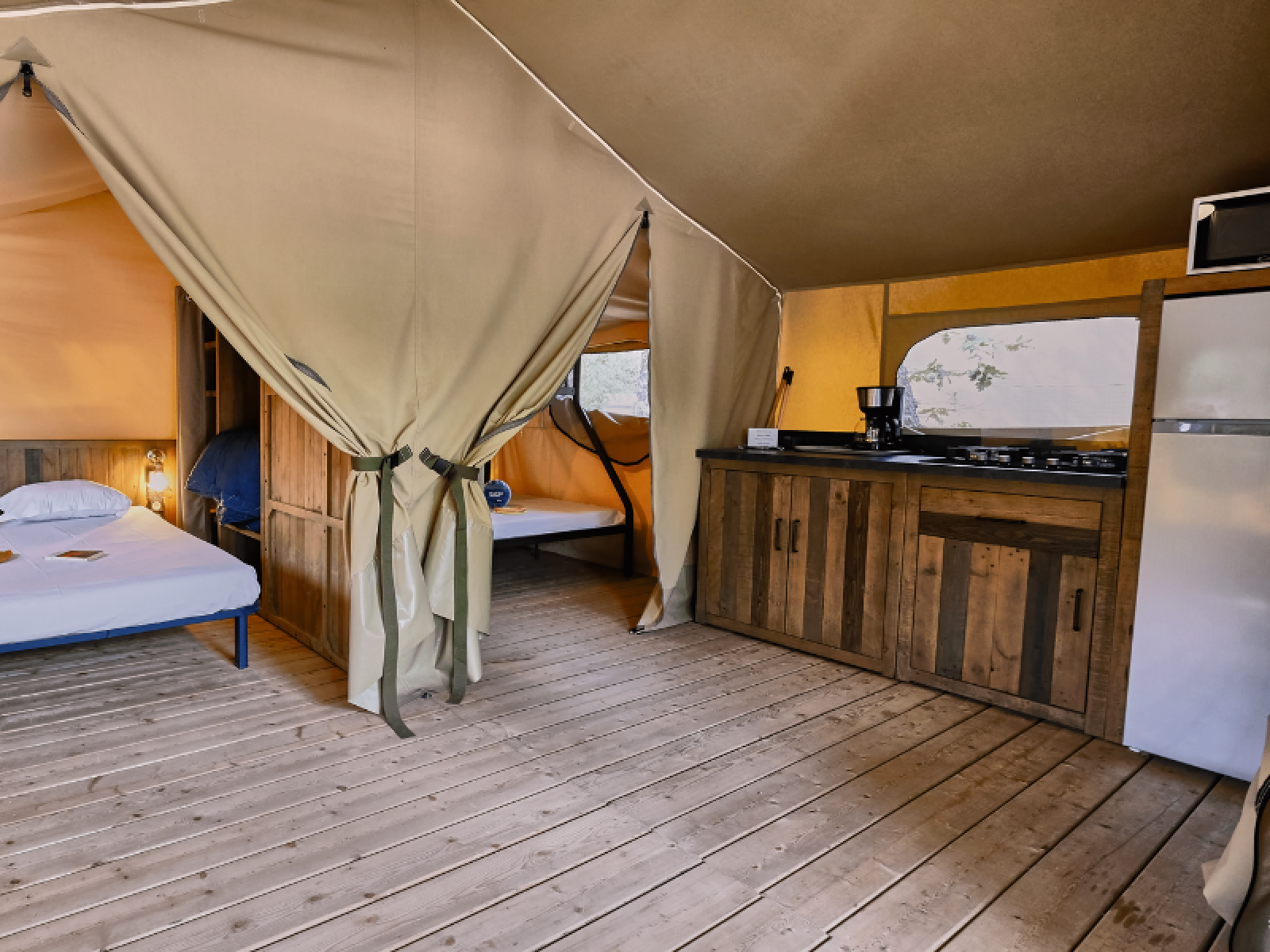 Interieur van de Lodge «COSY» safaritent op Domaine des Chênes Blancs in Frankrijk, met slaap- en keukenruimte.