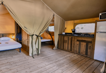 Indvendig udsigt af Lodge «COSY» safari-telt på Domaine des Chênes Blancs i Frankrig med sove- og køkkenområde.