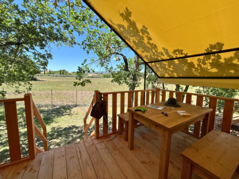 Outdoor terrace of the safari tent 'Bungalowtent' at Domaine des Chênes Blancs, France, with wooden table.