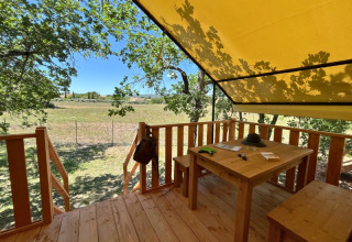 Udendørs terrasse ved safari teltet 'Bungalowtent' på Domaine des Chênes Blancs, med træbord og udsigt.