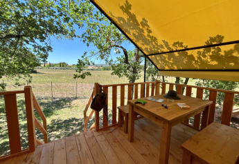 Udendørs terrasse ved safari teltet 'Bungalowtent' på Domaine des Chênes Blancs, med træbord og udsigt.