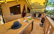 Overdekt houten terras bij safari tent 'Bungalowtent' op Domaine des Chênes Blancs in Frankrijk met stoelen.