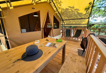 Udendørs terrasse ved en safari telt 'Bungalowtent' på Domaine des Chênes Blancs, Frankrig, med træmøbler.
