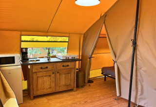 Interior of a Bungalowtent safari tent at Domaine des Chênes Blancs in France, featuring a small kitchen setup.