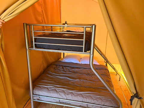 Inde i en safari 'Bungalowtent' på Domaine des Chênes Blancs, Frankrig, ses en køjeseng i teltet.