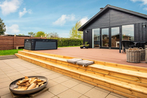 Terrasse en bois avec jacuzzi et brasero au gîte 4 personnes à Haderslev, Danemark, par temps ensoleillé.