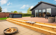 Terrasse en bois avec jacuzzi et brasero au gîte 4 personnes à Haderslev, Danemark, par temps ensoleillé.