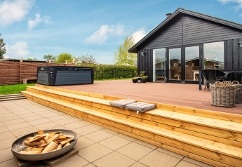 Terrasse en bois avec jacuzzi et brasero au gîte 4 personnes à Haderslev, Danemark, par temps ensoleillé.