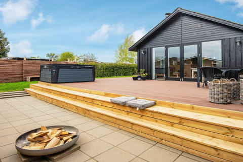 Terrasse en bois avec jacuzzi et brasero au gîte 4 personnes à Haderslev, Danemark, par temps ensoleillé.