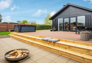 Terrasse en bois avec jacuzzi et brasero au gîte 4 personnes à Haderslev, Danemark, par temps ensoleillé.