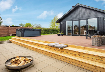 Houten terras met bubbelbad en vuurkorf bij 4-persoons vakantiehuis in Haderslev, Denemarken, op zonnige dag.